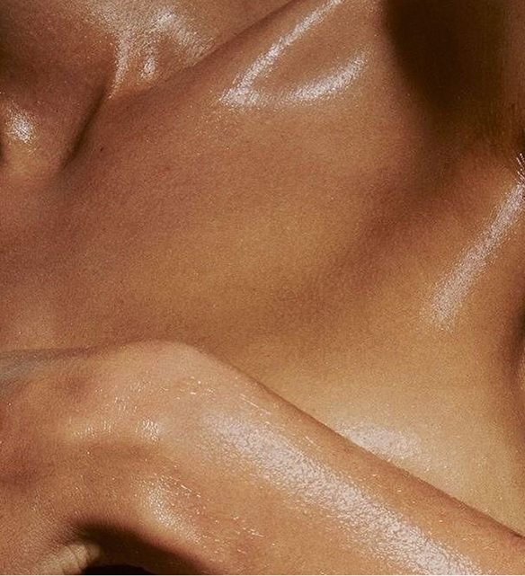 womens chest and hand covered with body oil